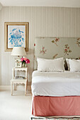 Floral headboard and gingham valance on bed in Cotswolds home, UK