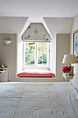 Embroidered bed linen and sunlit window seat in Cotswolds home, UK