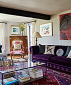 Purple sofa and glass coffee table in living room of Devon home, UK