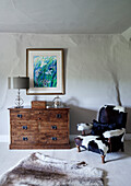 Upholstered armchair and wooden chest of drawers in whitewashed Devon home, UK