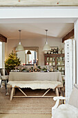 Cream pendant lights above dining table set for Christmas in West Sussex home, UK