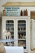 Vintage French sign and bottles in display cabinet West Sussex home, UK