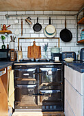Grey oven and pan rack in small kitchen of converted shipping container Bedford, UK
