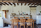 Wooden dining table under beamed ceiling in renovated Yorkshire farmhouse, UK