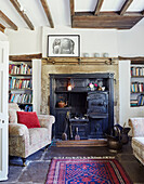 Armchair and bookshelves at traditional fireside in Yorkshire farmhouse, UK