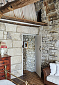 Exposed stone walls and open door in renovated Yorkshire farmhouse, UK