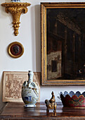 Oriental ornaments and gilt framed art on wooden sideboard in Foix townhouse Ariege, France