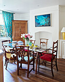 Glass dining table with mismatched vintage chairs in Northern home, UK