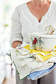 Mid section of woman holding bowl and folded linen in Northern home, UK