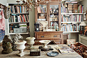 Glasvitrine und Bücher mit Pferdestatuen und Urnen in einem Haus in Somerset, UK