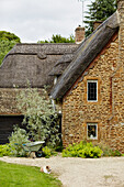 Stone exterior and chimney breast of thatched Oxfordshire farmhouse, UK
