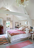 Double bed with patterned rugs and high ceiling in Oxfordshire farmhouse, UK