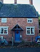 Blue front door and wooden porch of brick semi-detached terraced house, UK