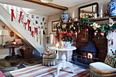 Christmas garland above lit woodburner with ribbons on staircase in entrance hall, UK