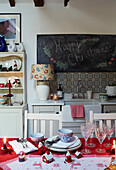'Happy Christmas' on blackboard above sink with glasses and crockery on table