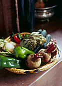 Vegetable basket containing beetroot green pepper chili cucumber and artichokes