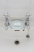 Chrome taps and soapdish on washbasin in Colchester family home, Essex, England, UK
