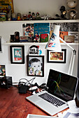 Artwork and ornaments with desk lamp and laptop computer on desk in Colchester studio Essex, England, UK