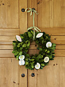 Christmas flower wreath hanging on wooden wardrobe in Herefordshire cottage, England, UK