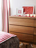 Lit candles and artwork on wooden chest of drawers in Polish bedroom