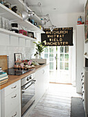 White galley kitchen with vintage kitchenware and black roller blind in Winchester home, Hampshire, UK