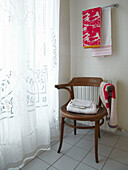 Vintage wooden chair with lace curtains in contemporary family home, France