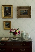 Paintings hanging above dresser with bouquet
