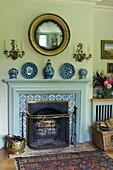 Tiled fireplace in rustic living room with decorative china plates and vase