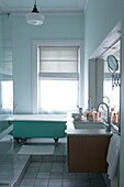 View into pale green bathroom with double vanity unit and green bath tub