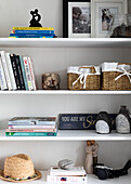 Familienfotos, Bücher und Ornamente auf Regalen in einem Haus in Reigate, Surrey, UK