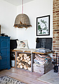 Salvaged packing crates for seating and log storage with antique wicker pendant shade in Colchester home Essex UK