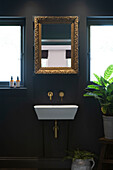 Ein vergoldeter Spiegel ist der zentrale Blickfang im Bad und lässt das Licht in den kleinen Raum einfallen