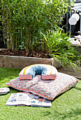 Child's reading cushion on astro turf lawn with bamboo in raised planter, Cardiff, Wales, UK