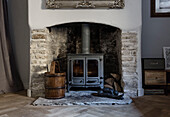 Woodburner with antique bucket in exposed stone fireplace Somerset home UK