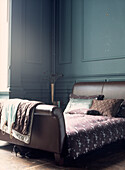 Painted wood paneled bedroom with leather bed and cotton bedlinen