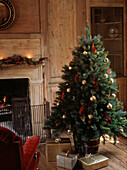 decorated Christmas tree in wood paneled living room with open fire