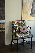 Crocheted cushion on retro print upholstered chair 