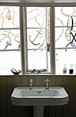 Nautical windows above pedestal wash basin in bathroom with tongue and groove panelling