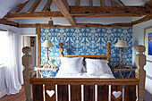 Hearts carved into wooden footboard of bed in blue room of timber framed Iden farmhouse, Rye, East Sussex, UK