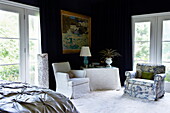 Armchair seating in dark blue bedroom of Massachusetts home, New England, USA