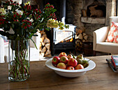 Bunch of flowers and bowl with fruits on table in living room