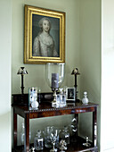 Glassware and gilt framed oil painting with antique wooden side table in Lincolnshire country house, England, UK