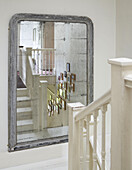 Framed pictures reflected in old mirror on staircase landing in Hereford home, England, UK