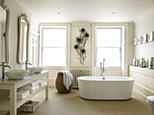 Freestanding bath with floral wall detail and double basins in bathroom of contemporary Bath home Somerset, England, UK