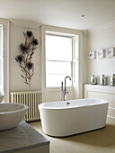 Freestanding bath with floral wall detail in bathroom of contemporary Bath home Somerset, England, UK