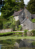 Stone farmhouse beside village pond in Perverells, Derbyshire, England, UK