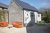 Outdoor furniture on gravel exterior of stone outhouse Wales, UK
