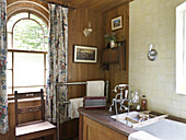 Arched window with floral curtains in bathroom of Shropshire chapel conversion England, UK