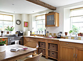 Sunlit windows of kitchen in Gloucestershire home with beamed ceiling England UK