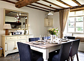 Esszimmertisch und bemalte Anrichte in einem Bauernhaus mit Balken in Gloucestershire England UK